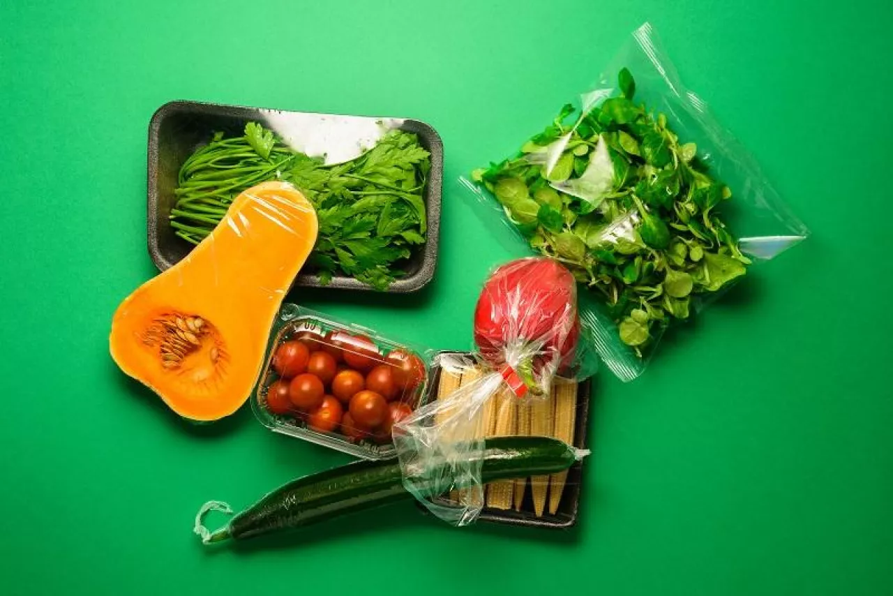 Fresh vegetables in plastic package. Zero waste, recycle concept. Plastic pollution. Green background