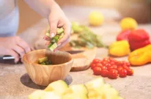 Close up shot of female hand putting ingredients for a salad in a bowl. Daily menu for pregnant woman. Horizontal shot. Selective focus