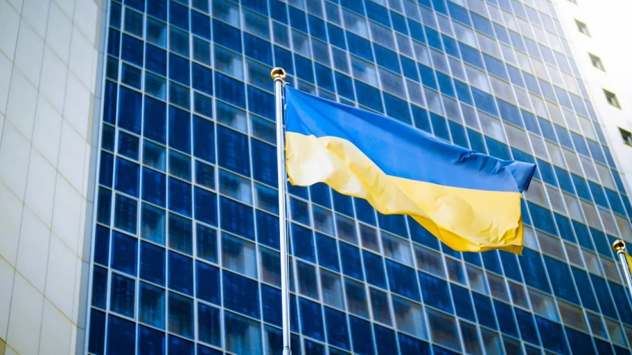 Photo of yellow and blue Ukrainian flag against modern business office building