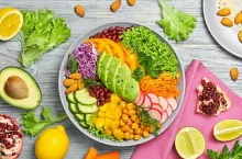 Buddha bowl salad with avocado, tomato, lettuce, cucumber, red cabbage, chickpeas, pomegranate. Paleo diet, healthy vegan and balanced food concept. Fresh rainbow mix green salad on wood