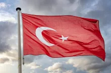 Turkey sign symbol. Turkish national flag on a pole waving against cloudy sky background.