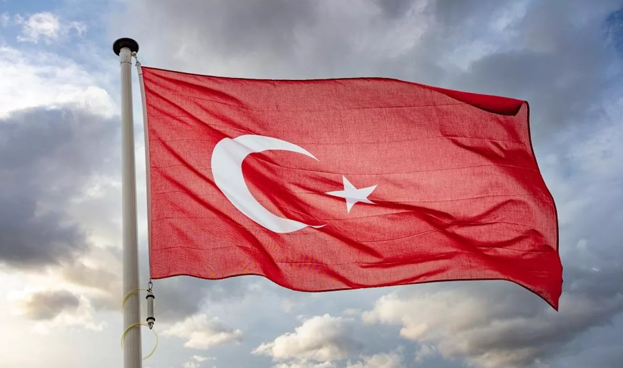 Turkey sign symbol. Turkish national flag on a pole waving against cloudy sky background.