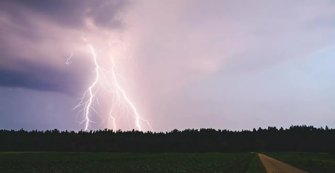 Lightning bolt at night over rural area. Agriculture fields.