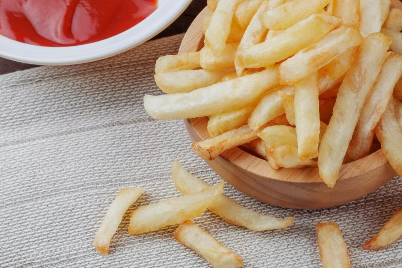 French fries in a bowl and sauce on tablecloth.