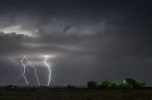 A large lightning strike at night in a rural area of Roswell, New Mexico framed against stormy skies.