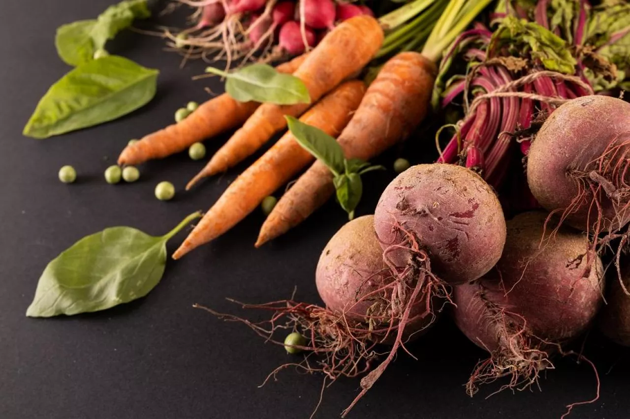 Close-up of carrots and beetroots with green peas and leaf vegetable on black background. unaltered, copy space, vegetable, healthy food, raw food, variation and organic concept.