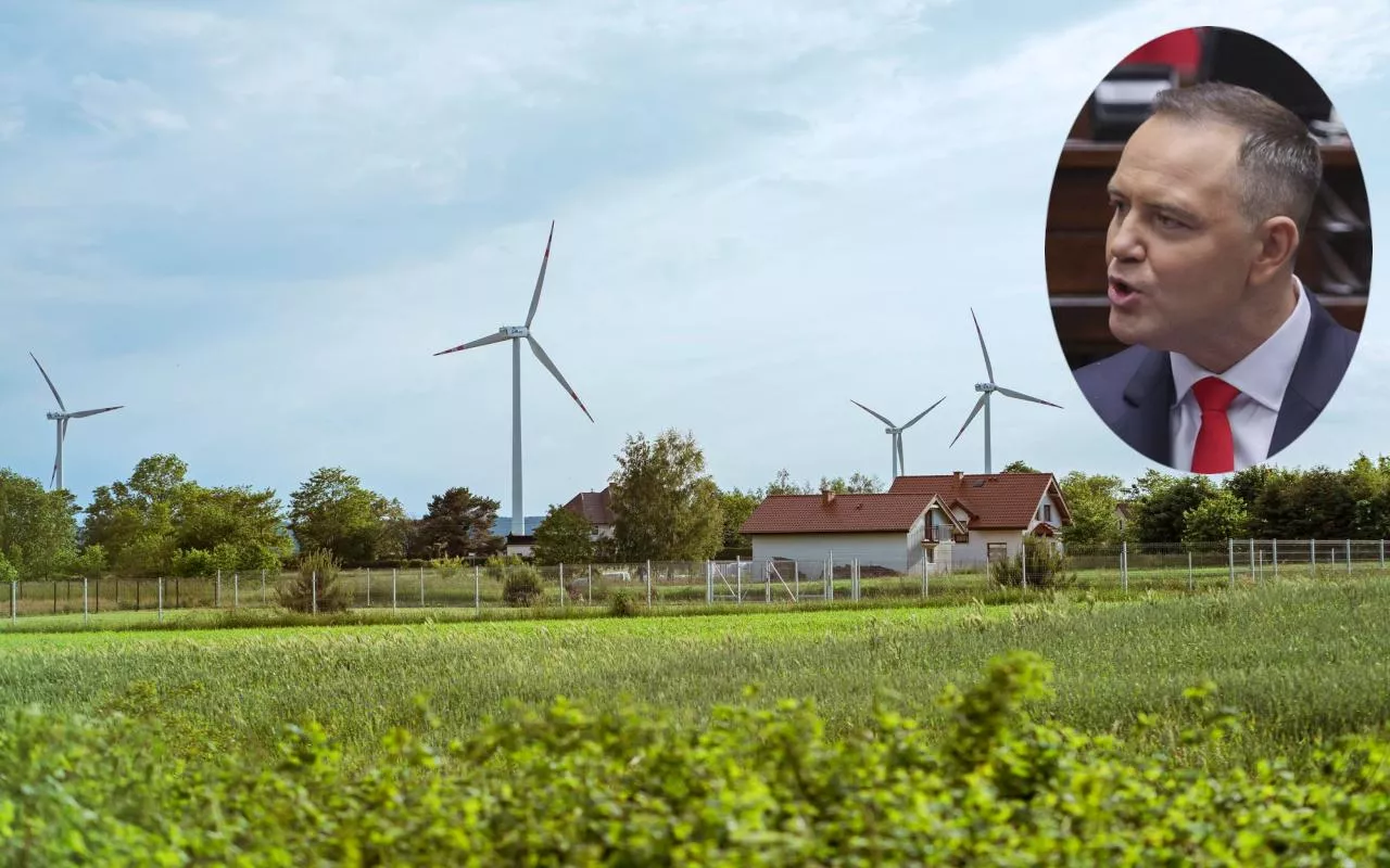 Widok na farmę wiatrową położoną w pobliżu zabudowań wiejskich. Na zdjęciu wmontowany wizerunek prezydenta Karola Nawrockiego, który zapowiedział weto wobec ustawy wiatrakowej.