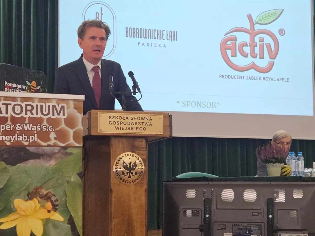 Mężczyzna w garniturze przed mównicą podczas konferencji