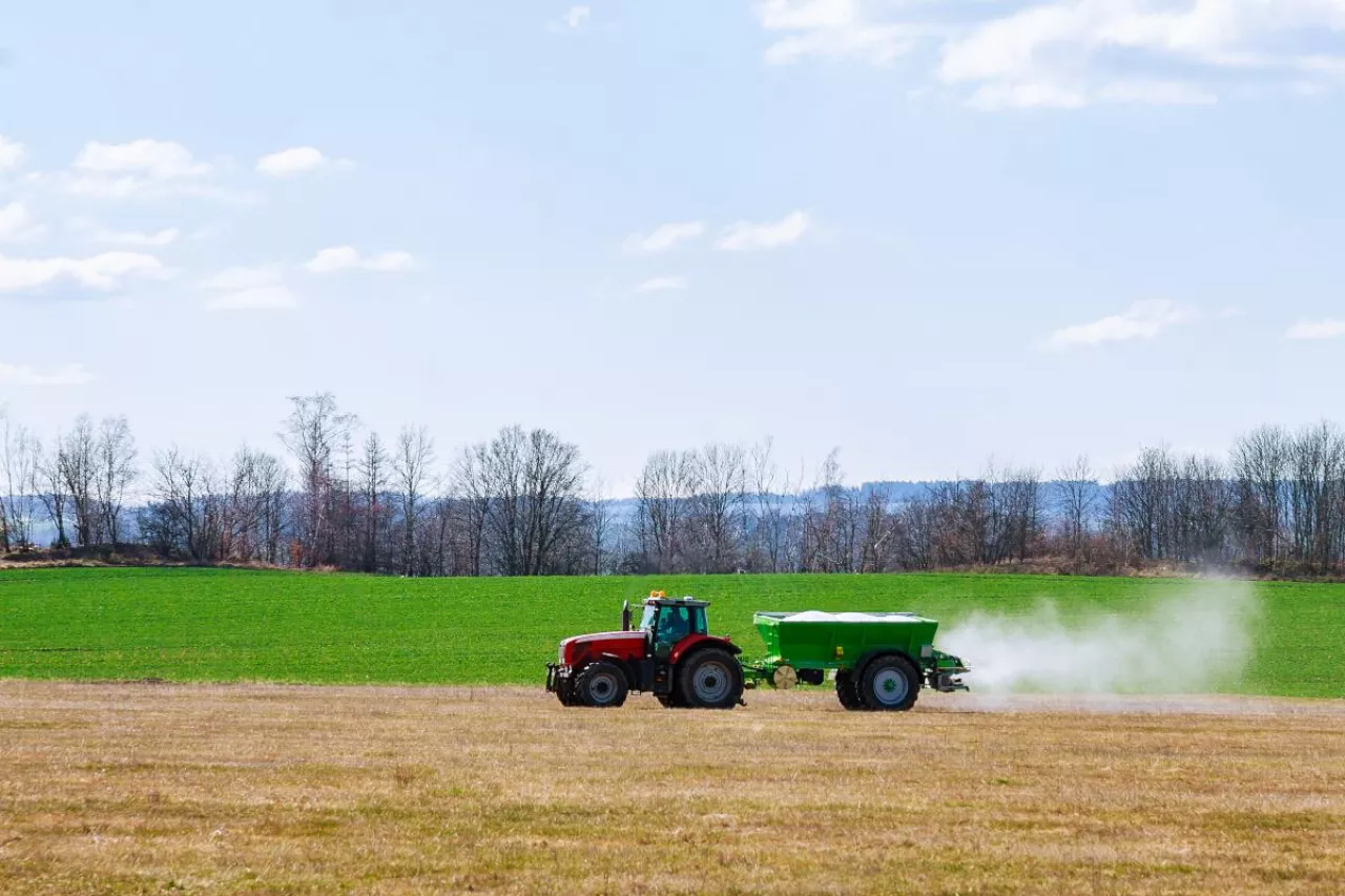 Ciągnik z rozsiewaczem nawozu podczas pracy na polu